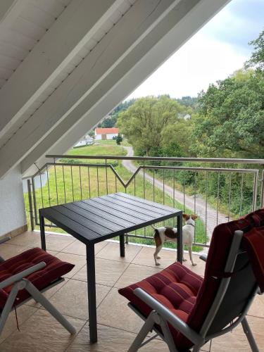 a dog standing on a porch with a table and chairs at Ferienwohnung Waldesrand in Rodenbach