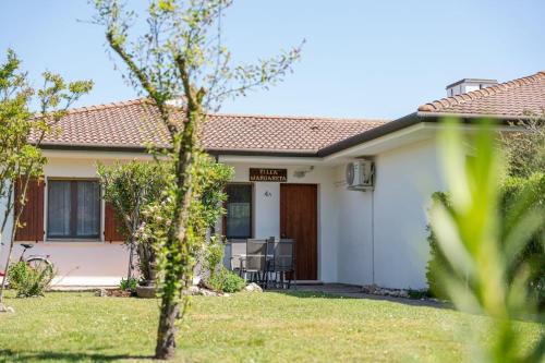 a small white house with a table and chairs in a yard at Margareta in Caleri