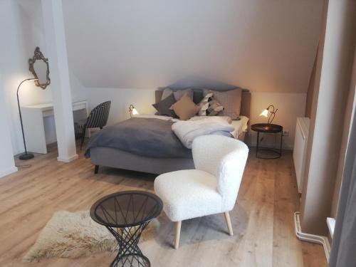 a bedroom with a bed and a white chair at Ferienwohnung Landidyll Heese in Langlingen