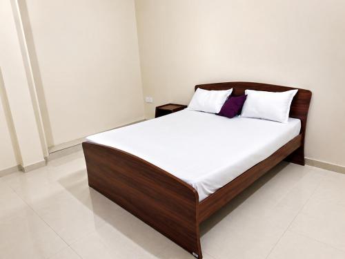 a bed with white sheets and purple pillows in a room at Princess Rose Villa in Vavuniya