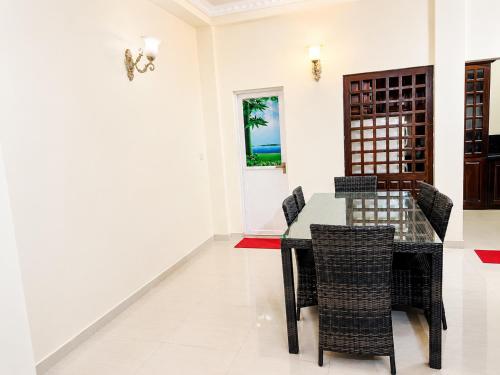 a dining room with a glass table and chairs at Princess Rose Villa in Vavuniya