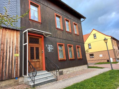 a black house with a wooden door and stairs at Ferienwohnung Fessel in Hasselfelde
