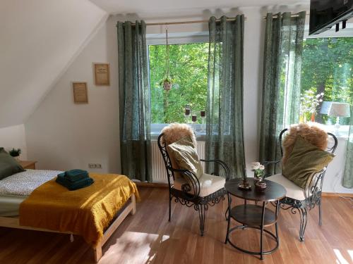 a bedroom with a bed and chairs and a window at Dorfstübli - gemütliche und ruhige Zimmer in Ortsrandlage in Alt Schönau