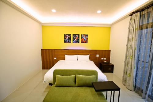 Un dormitorio con una cama y una pared amarilla. en Feng-Tian Inn, en Wujie