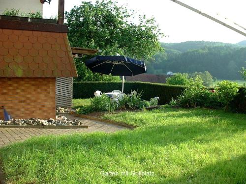 a patio with an umbrella in the grass at Ferienwohnung Hamel in Kirchlotheim