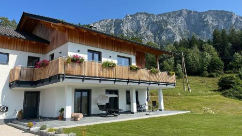 a white house with a balcony and a mountain at Wild und Wald Ferienwohnung in Steinbach am Attersee