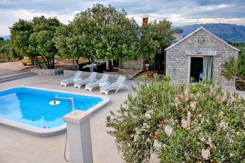una piscina al aire libre con sillas y una casa en Holiday Home Sweet Dreams, en Pučišća