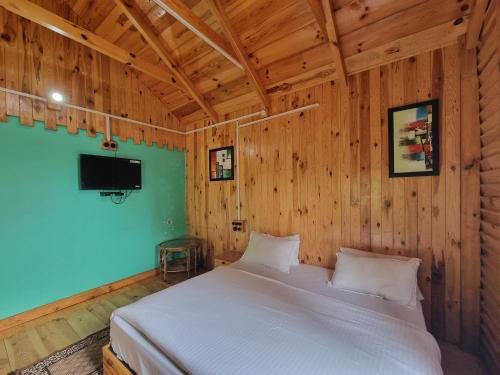 a bedroom with a white bed in a wooden wall at Mid Conifer Cottage Villa in Dalhousie