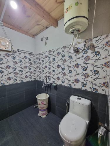a bathroom with a toilet and a wall with a wallpaper at Mid Conifer Cottage Villa in Dalhousie
