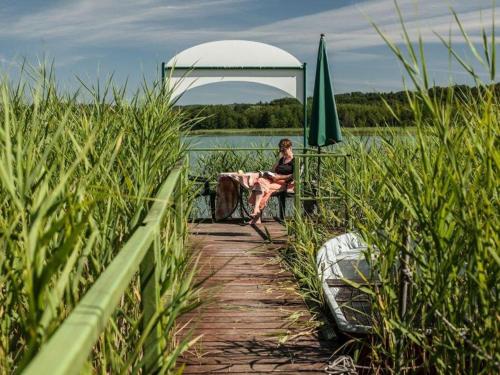 a woman sitting on a dock next to the water at Chalet am See in Waldsieversdorf