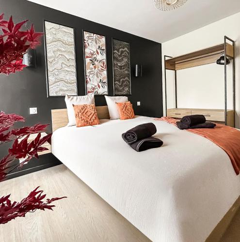 a bedroom with a large white bed with black walls at T2 lumineux, moderne, calme & central à Montargis in Montargis