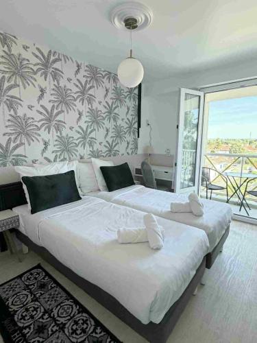 a bedroom with a large white bed and a balcony at Les Cols Verts - Logis Hôtels in La Tranche-sur-Mer