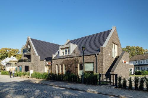 a brick house with a black roof on a street at Ferienwohnung Schietbüdel in Born