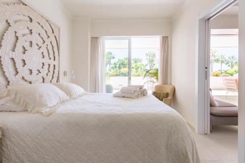 a white bedroom with a large bed and a window at Apartamentos Guadalpin Boutique in Marbella