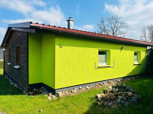 a yellow and green house with a yard at Ferienhaus SeeKrosch in Göhren-Lebbin