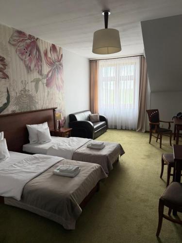 a hotel room with two beds and a couch at Hotel Neo Międzyrzecz in Międzyrzecz