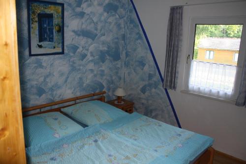 a bedroom with a bed with a blue comforter and a window at Ferienhaus Stechlinsee 1 in Stechlin