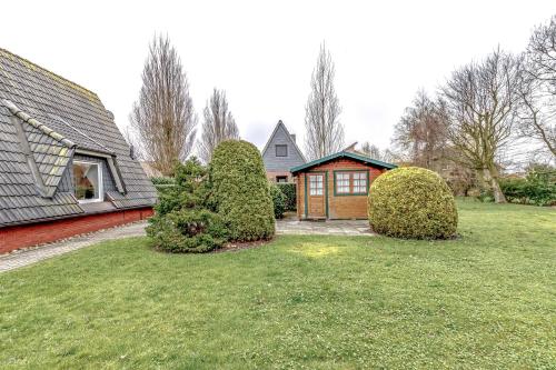 a house with two bushes in front of a yard at Ferienhaus Mina in Neuharlingersiel