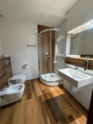 a bathroom with a shower and two sinks and a toilet at Hotel Neo Międzyrzecz in Międzyrzecz