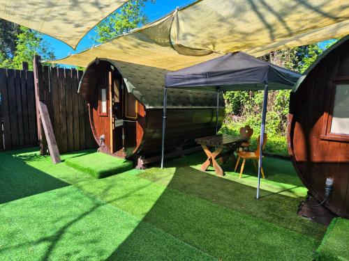a small tent with a table and an umbrella at Mini Hotel Übernachten Im Gurkenfass in Lübbenau