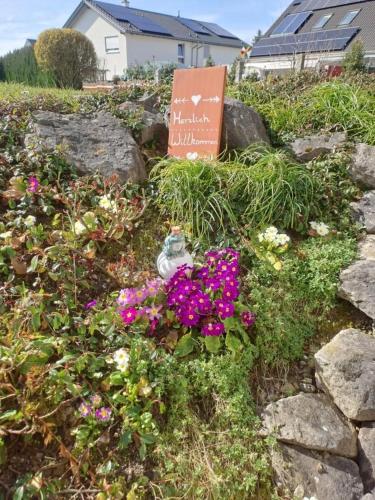 a garden with flowers and a sign in the grass at Ferienwohnung Groß in Bermatingen