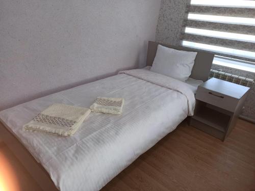 a small bedroom with a bed with two towels on it at Мотель Эмир in Pokrovka