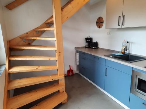 a wooden staircase in a kitchen with blue cabinets at Kastanienhof Lübben in Lübben