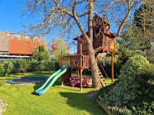 a tree house with a slide in a yard at Ferienwohnung "Christina" in Steinkirchen