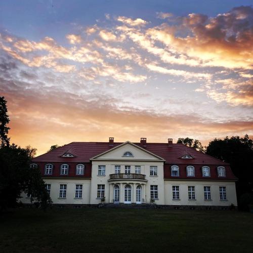 a large white house with a sunset in the background at Gutshaus Gevezin in Blankenhof
