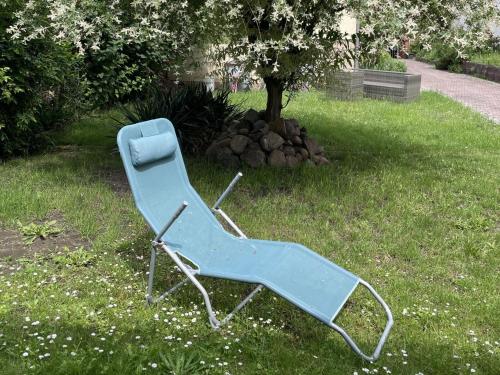a blue chair sitting in the grass next to a tree at Haus Delphinen in Lübben