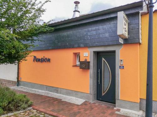 ein orangefarbenes Gebäude mit einer Tür davor in der Unterkunft Pension Kai in Ribnitz-Damgarten