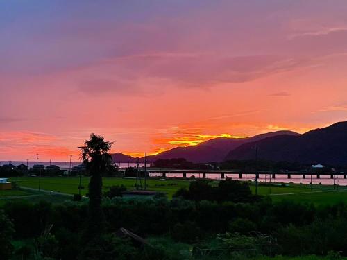a sunset over a body of water with a palm tree at 音毬 - Otomari - in Miyazu