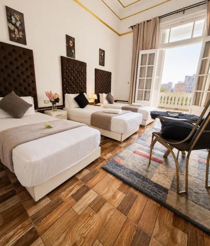 a large bedroom with two beds and a chair at pal ace talaat harb in Cairo