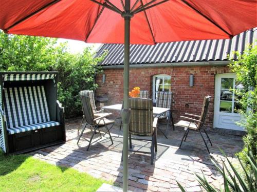 a red umbrella on a patio with a table and chairs at Ferienwohnung Galerie 1 in Hakendorferwurp