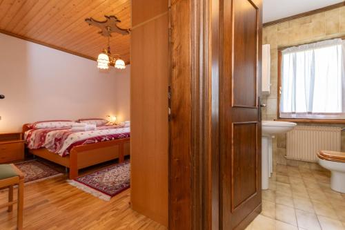 a bedroom with a bed and a bathroom with a sink at Ciase Ai Ronch in Falcade
