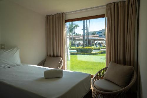 a bedroom with a bed and a window with a view of a yard at Grand Oca Maragogi All Inclusive Resort in Maragogi