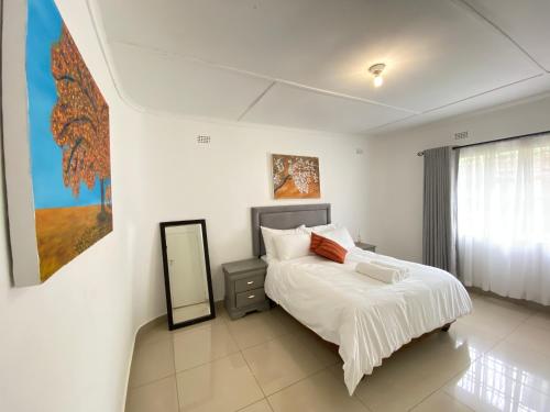 a white bedroom with a bed and a mirror at Meyrick Bed and Breakfast in Harare