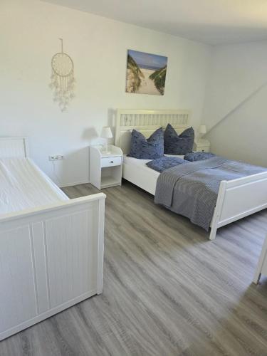 a white bedroom with a large bed with blue pillows at Ferienwohnung Ahoi in Langwedel