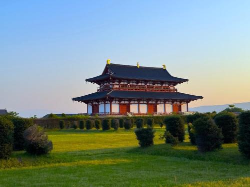 a chinese building in a field of grass at 平城空間 - Heijo Space in Nara
