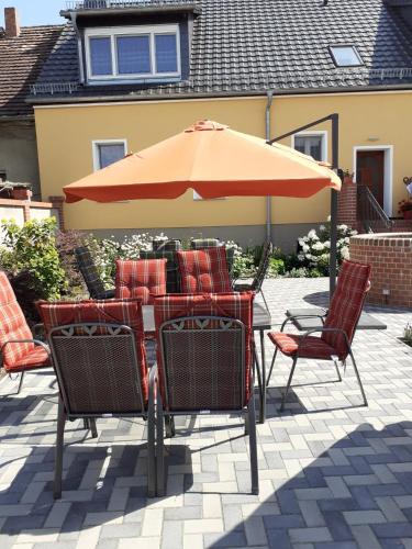 a table with chairs and an umbrella on a patio at Ferienwohnungen Kusche in Stennewitz