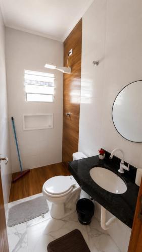 a bathroom with a toilet and a sink and a mirror at Beach House 96 in Itanhaém