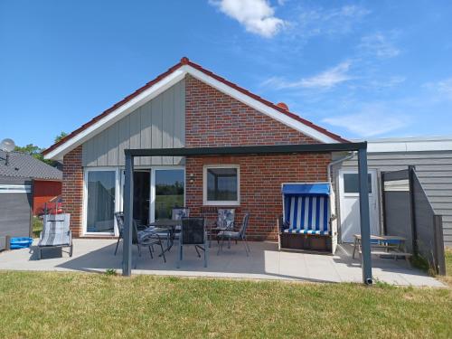 a house with a patio with chairs and a grill at Ferienhaus Weitblick in Sehestedt