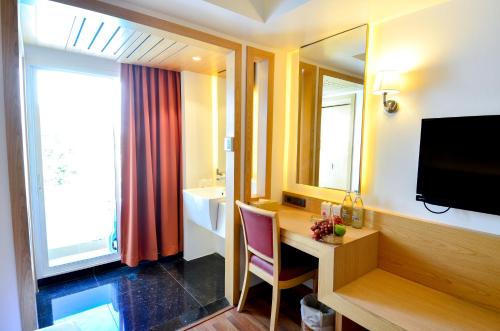 a hotel room with a desk and a sink and a mirror at Viva Hotel Songkhla in Songkhla