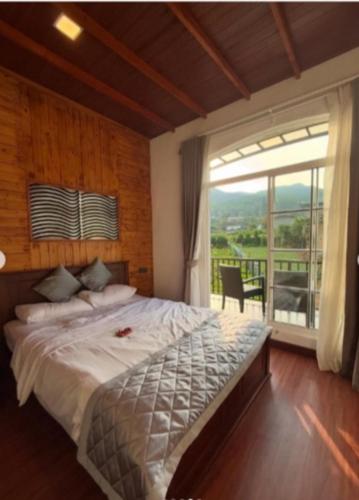 a bedroom with a large bed and a large window at Friendly Hills Hotel in Nuwara Eliya