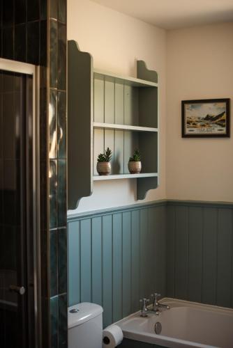 a bathroom with a sink and a toilet and shelves at Penlarach House in Oban