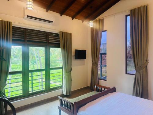 a bedroom with a bed and large windows at Jungle Breeze Villa in Melsiripura