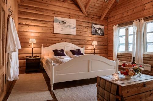 a bedroom with a white bed in a log cabin at Phillipshaugen Lodge in Øksendalsøra