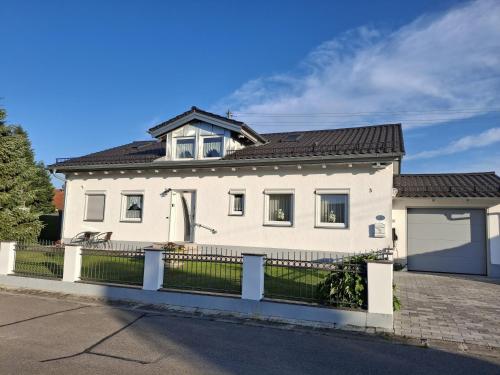 a white house with a fence in front of it at Ferienwohnung an der Singold in Holzhausen bei Buchloe