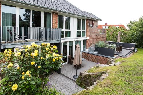 a house with a deck with a umbrella and flowers at Riff5 Wohnung 6 in Borkum