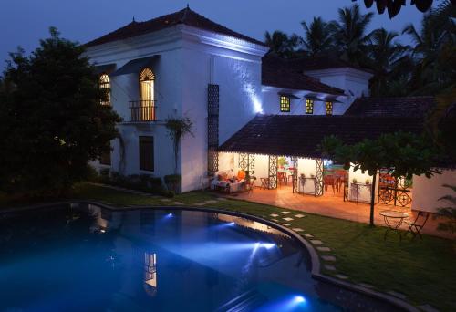 una casa con piscina di notte di Siolim House a Siolim